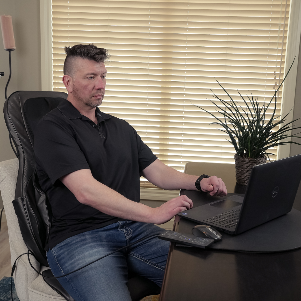A man on his laptop working while sitting on his BACKplus® Shiatsu Neck and Back Massager With Air Compression Chair.