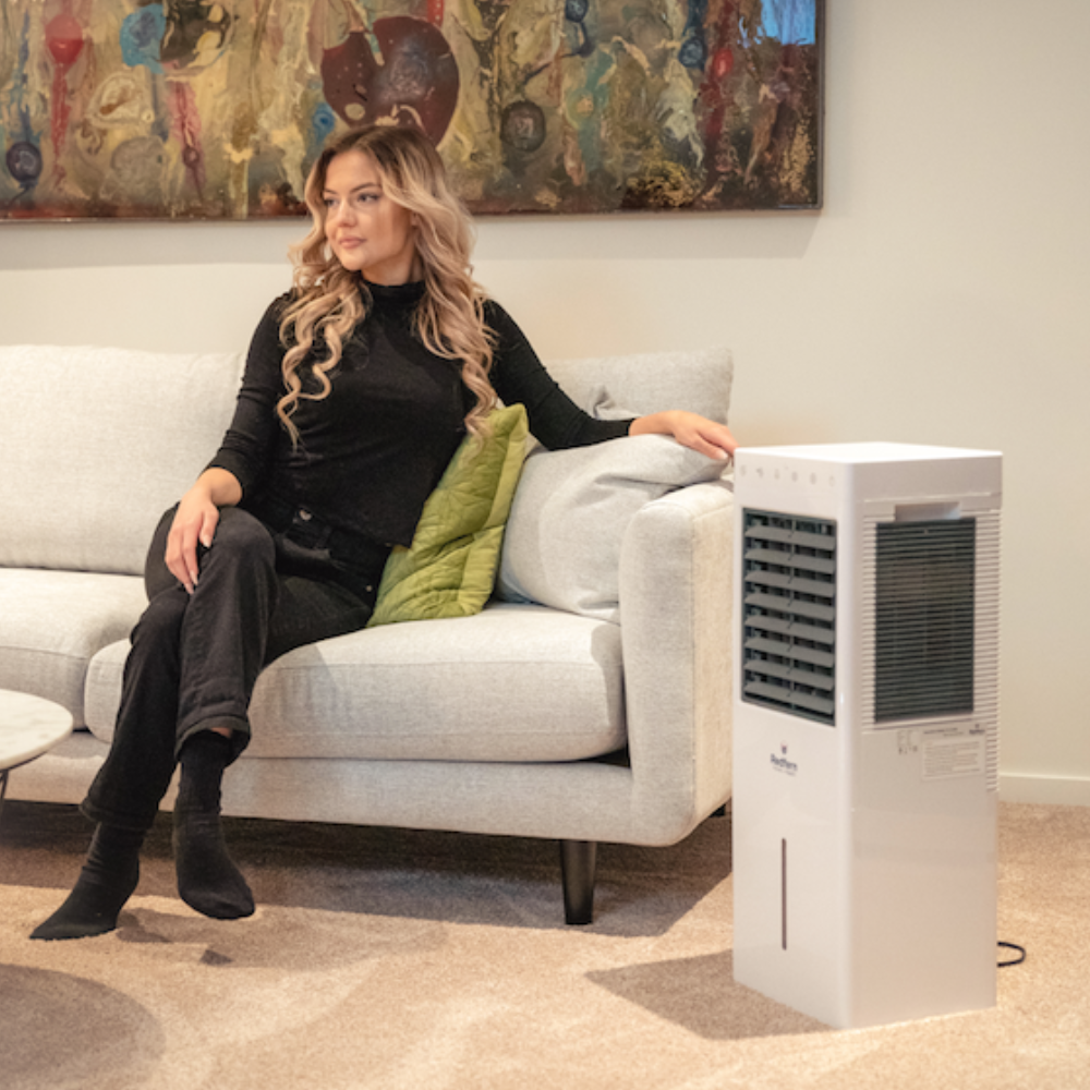 Woman sitting on her couch next to the iQ Pure Breeze Air Cooler