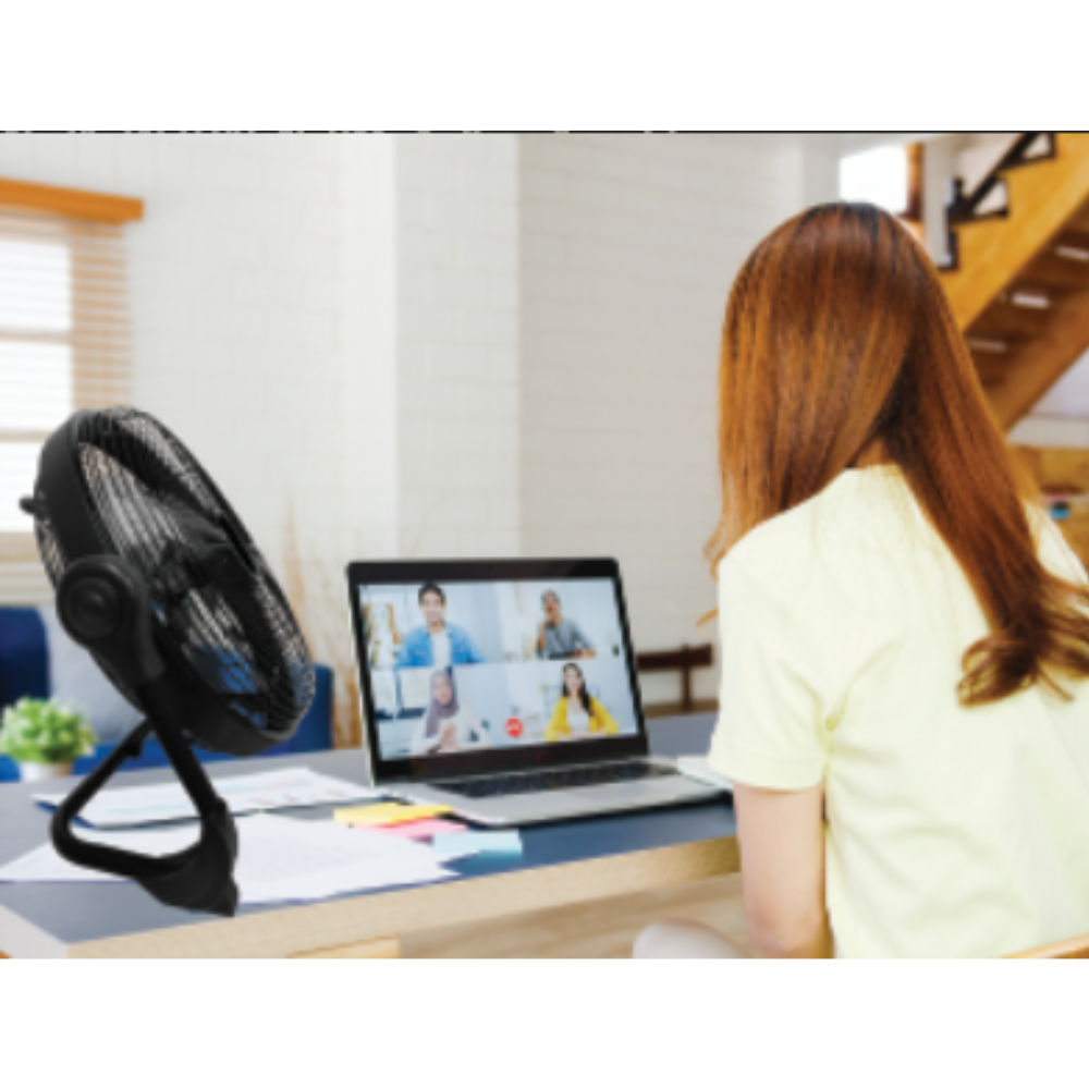 Woman using the iQ Rechargeable Floor Fan while working on her laptop