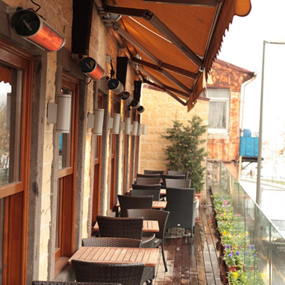 Multiple Veito Heaters mounted on a wall of a patio with chairs and tables