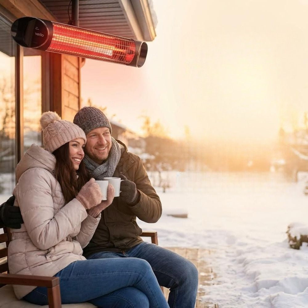 Couple sitting outside enjoying a drink while staying warm under their ceiling mounted Veito Blade Heater